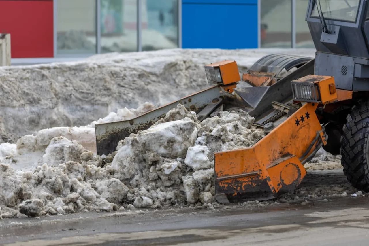 Industrial snow melter machine on-site, melting stacked commercial snow to meltwater for storm-drain discharge — Canada.