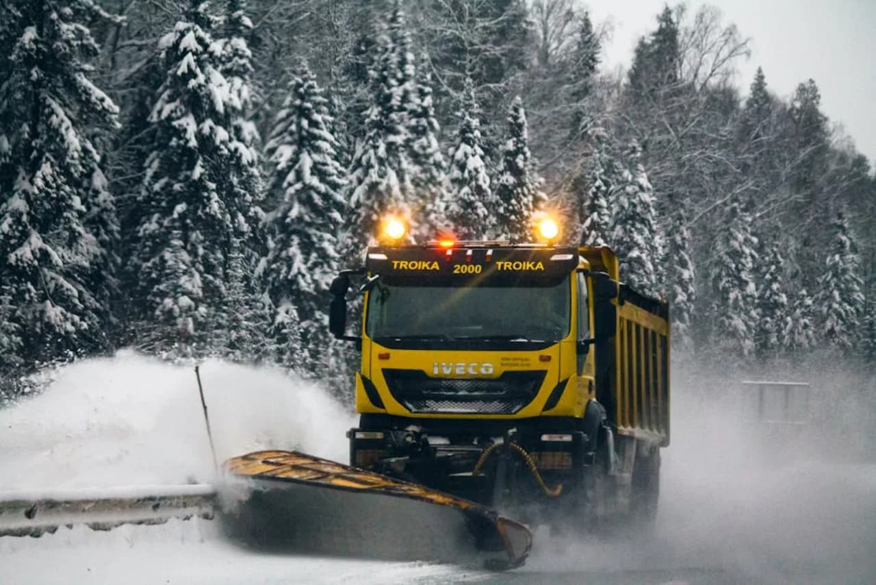 Truck-mounted snow plow with V-blade clearing a commercial parking lot in Canada — heavy winter operation.
