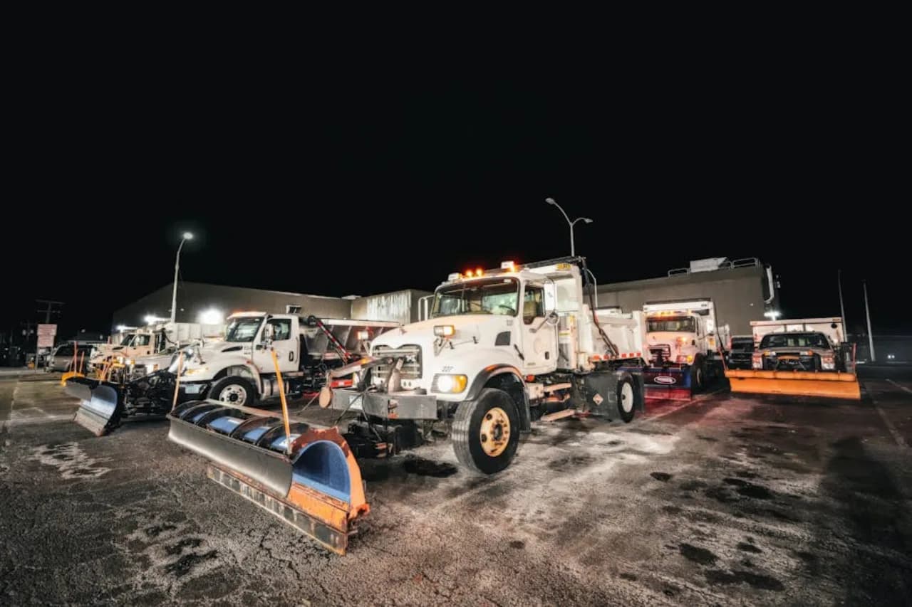 snow.ca commercial equipment yard at dusk — plow trucks, skid-steers, salt spreaders staged for the next Canadian storm.