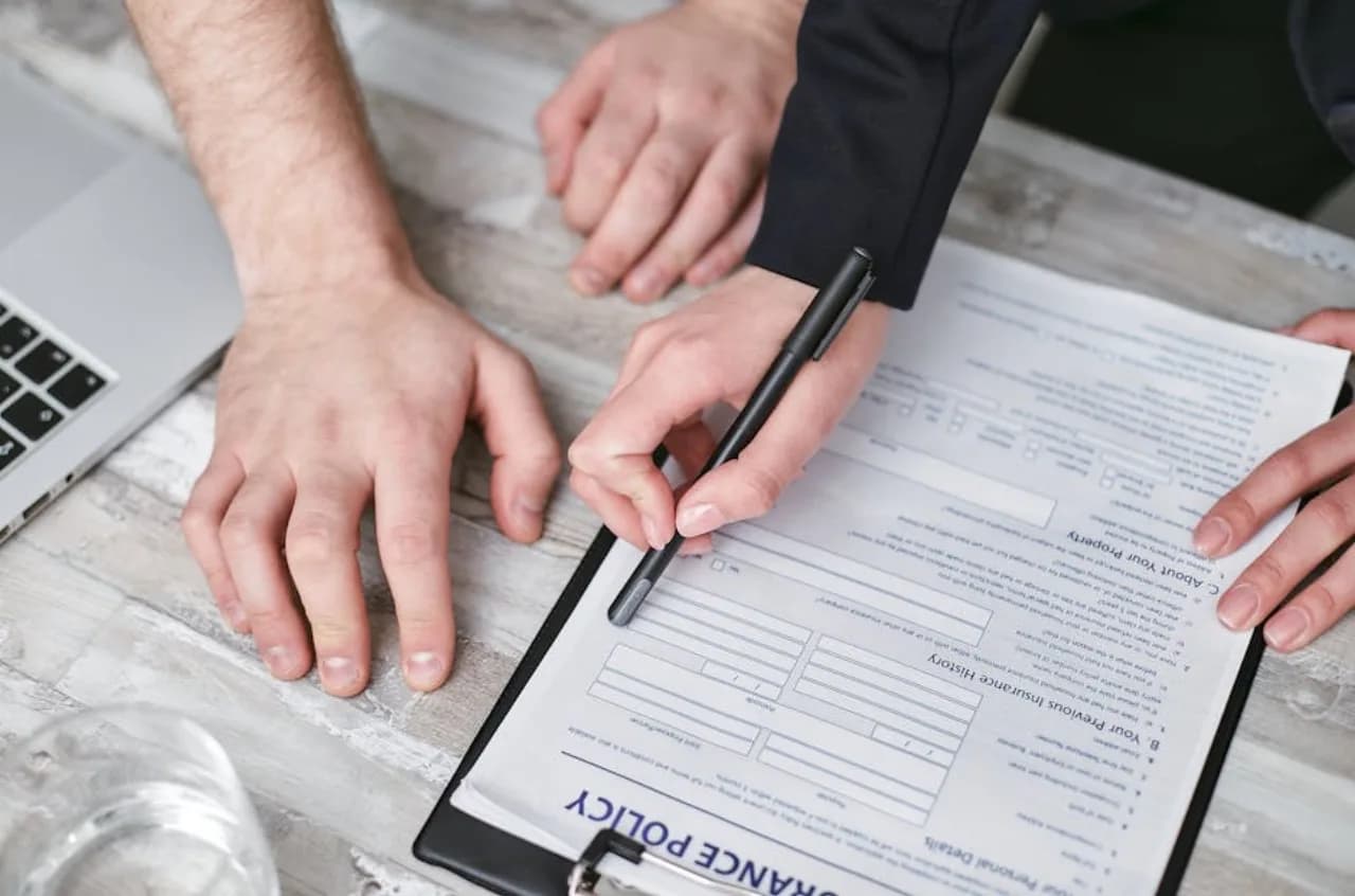 Un gestionnaire de propriété et un courtier révisent ensemble une police d’assurance sur un bureau — contexte de responsabilité civile et de couverture glissades-et-chutes pour les contrats hivernaux snow.ca au Canada.