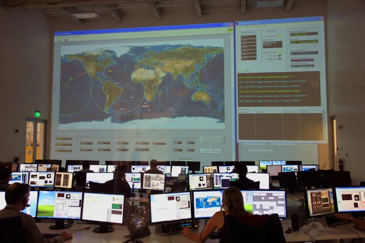Une salle de contrôle d’opérations avec une carte météo mondiale projetée et plusieurs postes de répartition — contexte de radar de tempête et de routage pour le Cabinet d’opérations snow.ca dans 80+ dépôts canadiens.