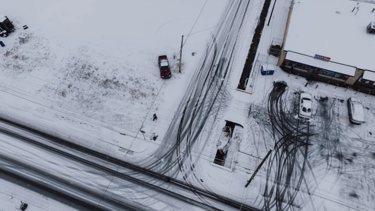 Skid-steer with 12-foot snow pusher box clearing a Canadian commercial parking lot at peak storm operation.