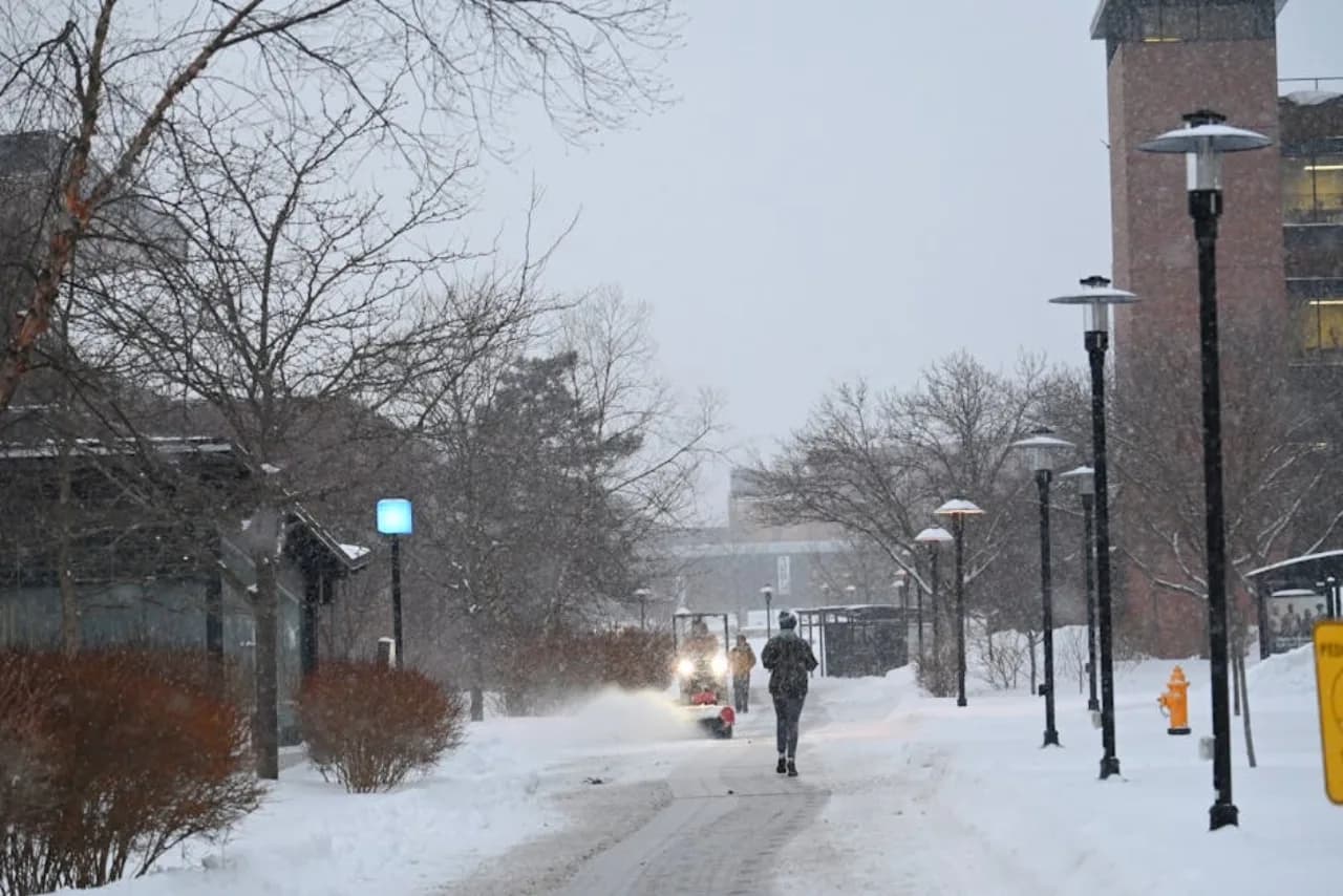 Sidewalk snow removal crew with walk-behind thrower clearing condo association walkways before morning rush — Canada.